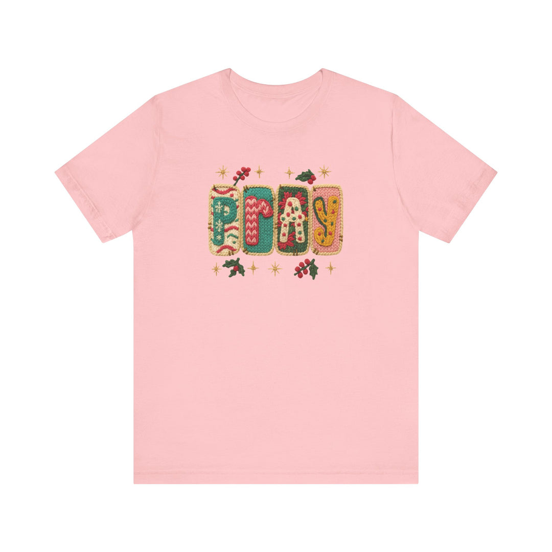 Pale-pink Pray Tee with holiday-patterned letters and holly accents, offering a soft, classic fit—perfect for festive, faith-inspired fashion.