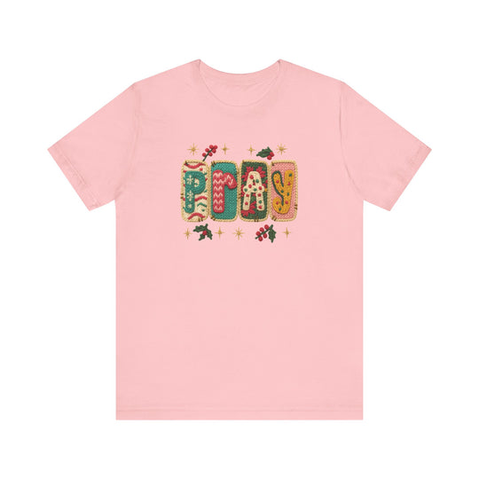 Pale-pink Pray Tee with holiday-patterned letters and holly accents, offering a soft, classic fit—perfect for festive, faith-inspired fashion.