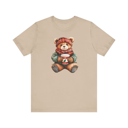 Old Money Christmas Bear Tee featuring a teddy bear in a red hat and scarf, holding a holiday cup, printed on a soft beige short-sleeve T-shirt.