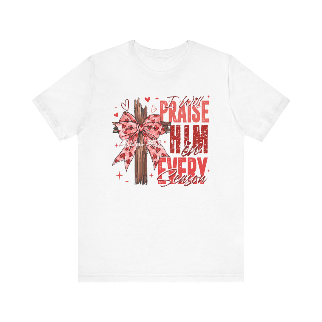 Praise in Every Season Heart Tee featuring a stylized wooden cross with a pink heart-patterned bow, red text, and Psalm 148:2 reference. Comfortable, durable, unisex fit.