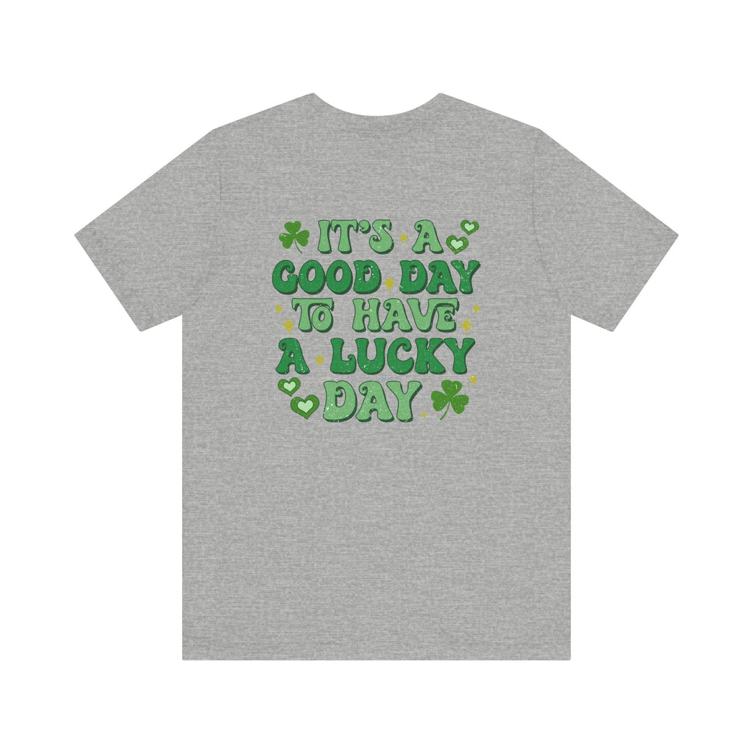 Good Day Lucky Day Tee, featuring green text and a clover on the back of a grey t-shirt, offering a soft, unisex fit.
