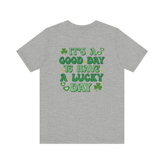 Good Day Lucky Day Tee, featuring green text and a clover on the back of a grey t-shirt, offering a soft, unisex fit.