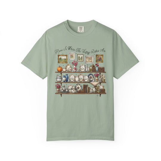 Vintage Dishes Tee featuring a cozy vintage illustration of shelves with antique china and decor, complemented by the phrase “Home Is Where The Vintage Dishes Are.”