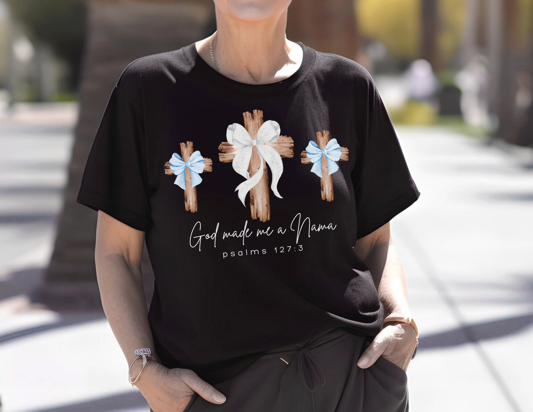 Person wearing God Made Me a Nana tee featuring rustic cross design, accessorized with bracelet and watch, showcasing Comfort Colors' relaxed, durable fit.
