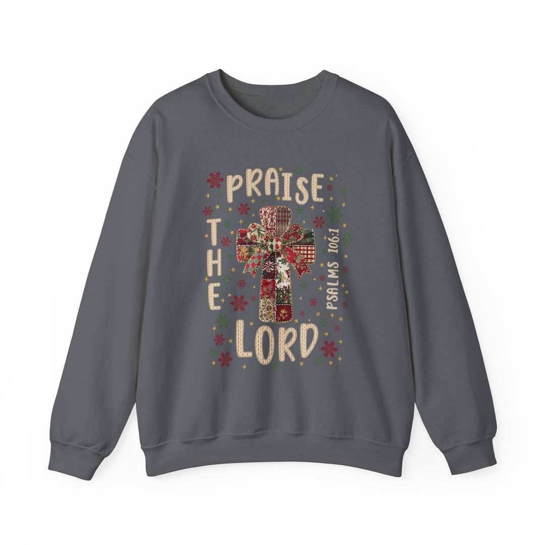 Charcoal-gray crewneck sweatshirt with a Christmas-style patchwork cross, festive motifs, PRAISE THE LORD text, and PSALMS 106:1 reference. Cozy, durable design.