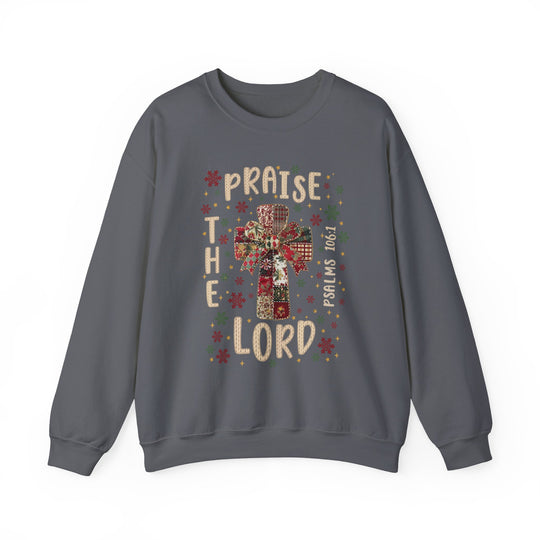 Charcoal-gray crewneck sweatshirt with a Christmas-style patchwork cross, festive motifs, PRAISE THE LORD text, and PSALMS 106:1 reference. Cozy, durable design.