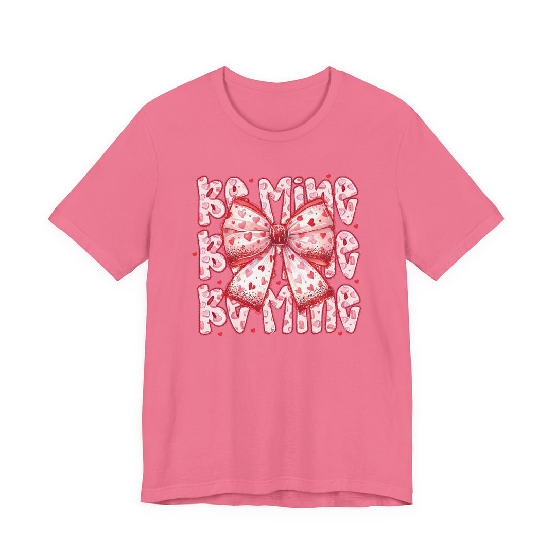 Be Mine Tee with heart-spattered bow and BE MINE text, perfect for Valentine's Day. Classic unisex fit, soft cotton, ribbed collar, and durable stitching.