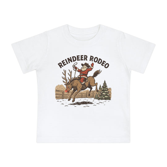 Reindeer Rodeo Baby Tee features Santa as a cowboy riding a reindeer, with REINDEER RODEO text, on a soft, durable, shrink-resistant cotton shirt for babies.
