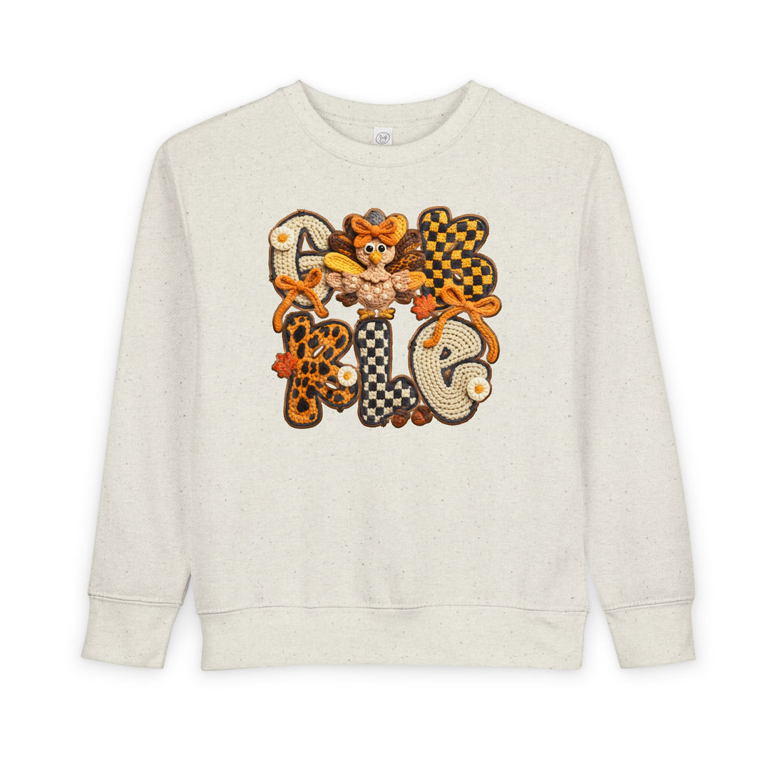 Cream-speckled toddler sweatshirt with GOBBLE in patchwork letters and a cartoon turkey, perfect for cozy, stylish autumn wear from Faith Family Designs.