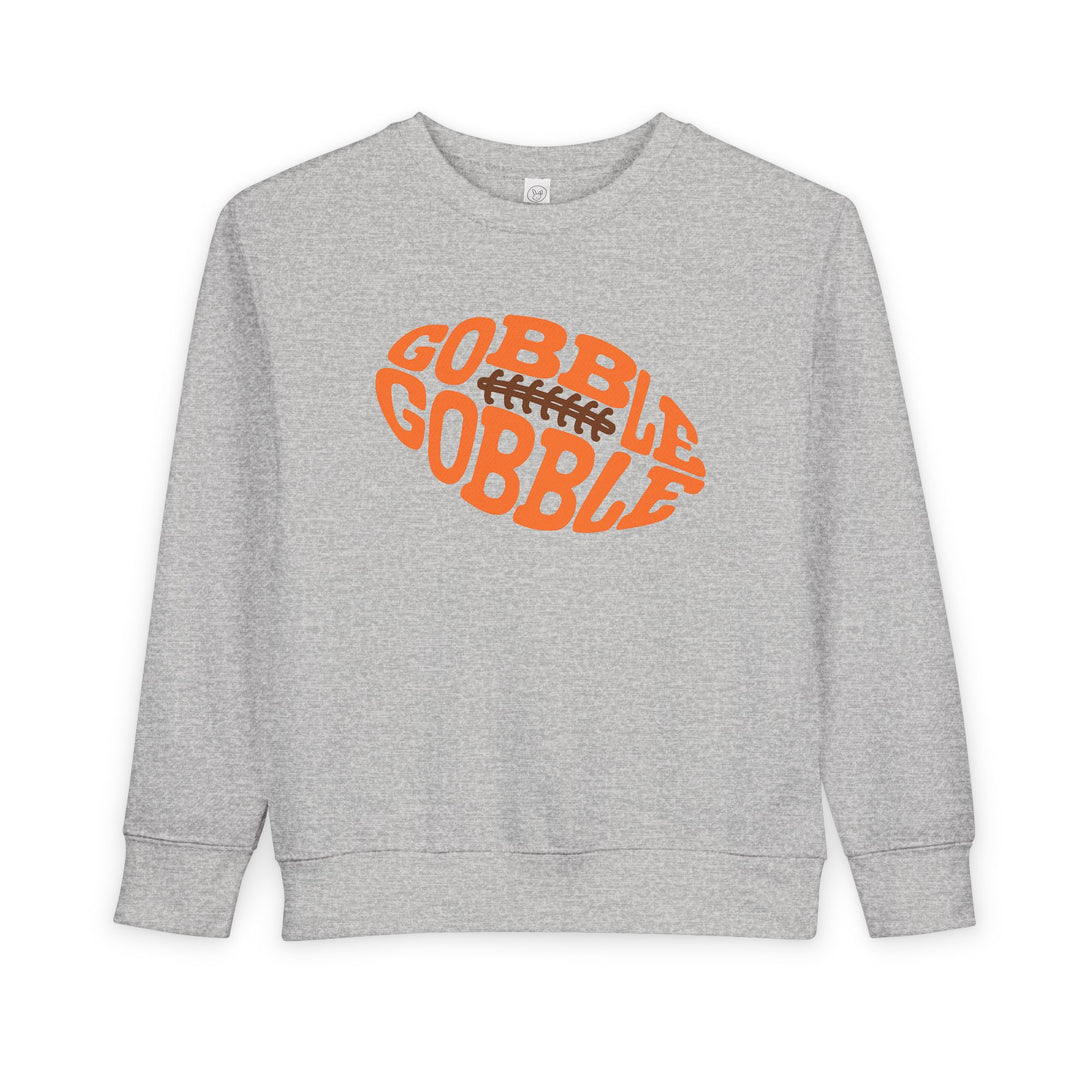 Heather-gray toddler sweatshirt with a football-shaped graphic saying “GOBBLE GOBBLE” in orange, blending warmth and playful Thanksgiving style.