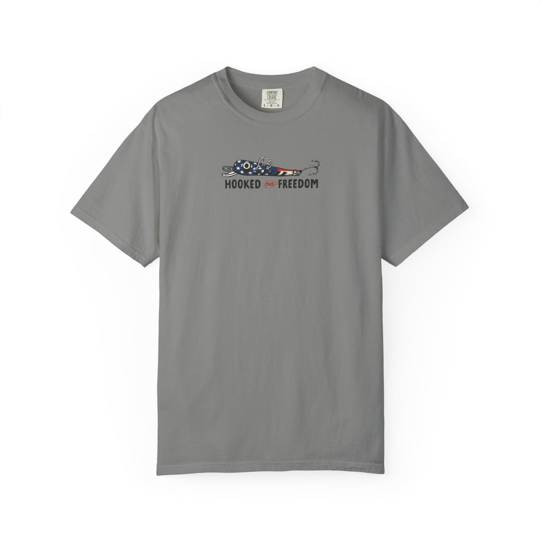 Hooked on Freedom Tee: Gray Comfort Colors t-shirt featuring a stars-and-stripes fishing lure graphic with HOOKED on FREEDOM slogan beneath. Relaxed fit, durable, 100% cotton.