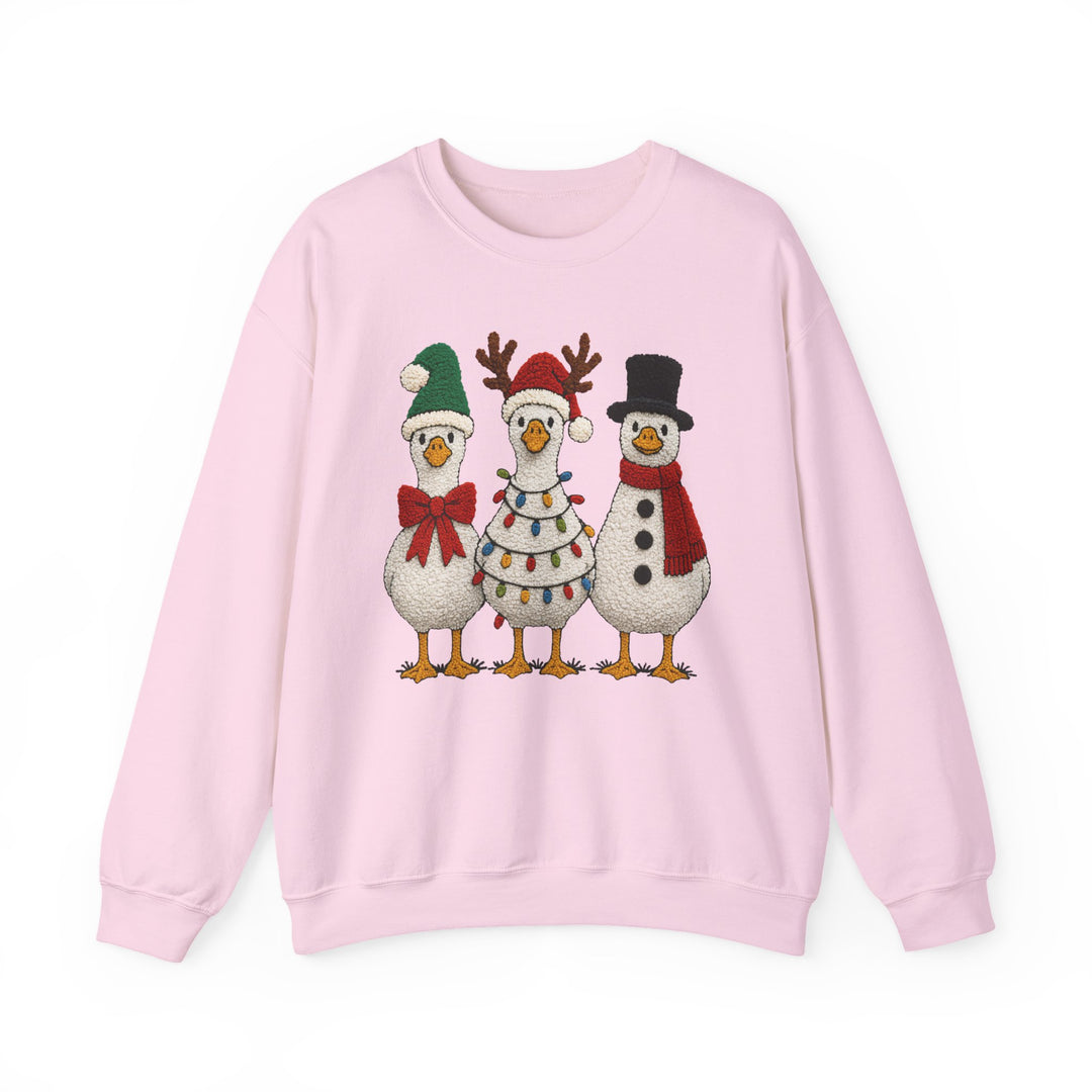 Light-pink crewneck sweatshirt featuring three festive geese in holiday attire: Santa-style, reindeer antlers, and snowman theme, perfect for Christmas cheer.