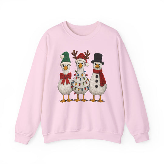 Light-pink crewneck sweatshirt featuring three festive geese in holiday attire: Santa-style, reindeer antlers, and snowman theme, perfect for Christmas cheer.