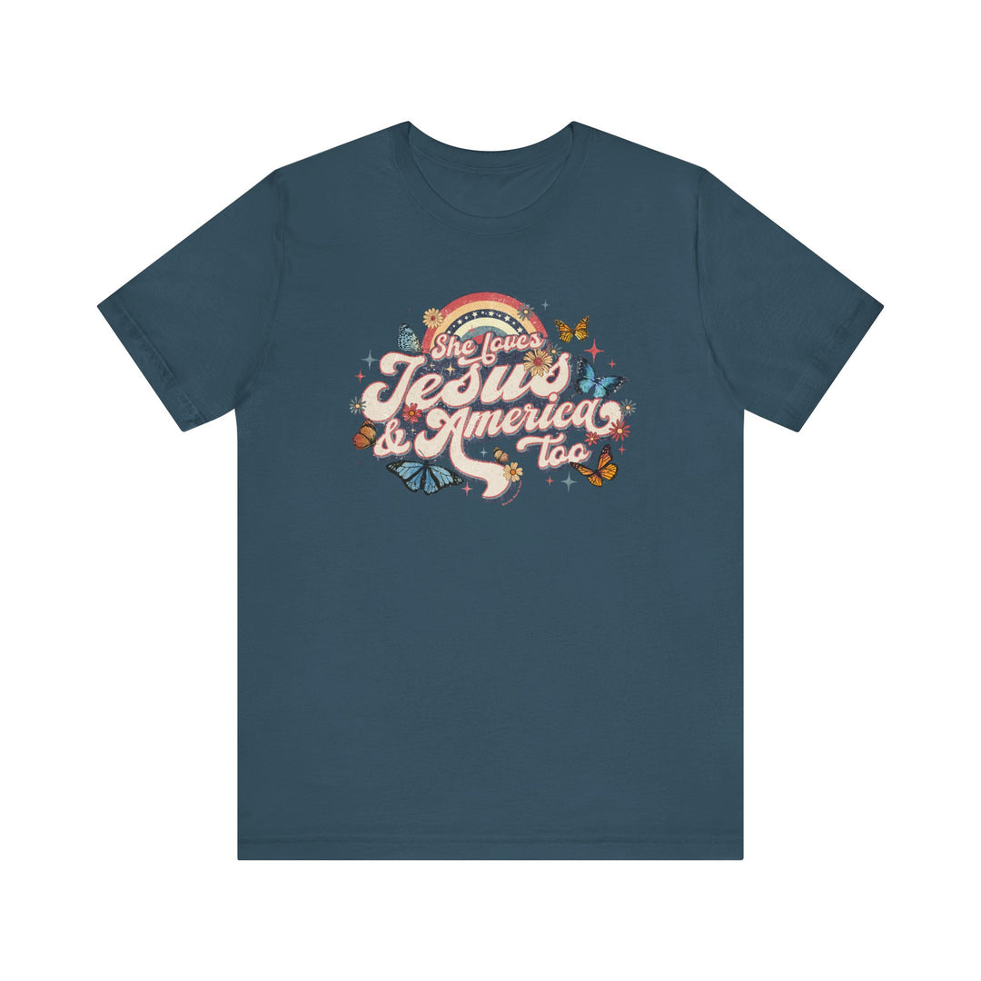 A She Loves Jesus and America Tee featuring a blue t-shirt with a graphic design of butterflies and flowers. Unisex jersey tee with ribbed knit collars, taping on shoulders, and tear away label. Made of 100% Airlume combed and ringspun cotton.