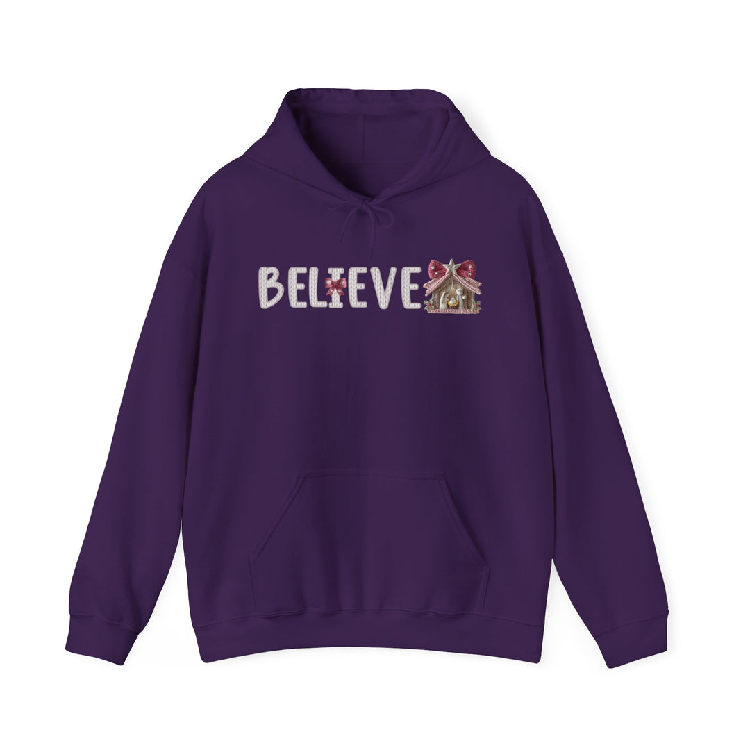 Deep-purple Believe Hoodie with kangaroo pocket, drawstring hood; features BELIEVE in white-knit letters, candy-cane I, gingerbread-house E, embodying festive charm.