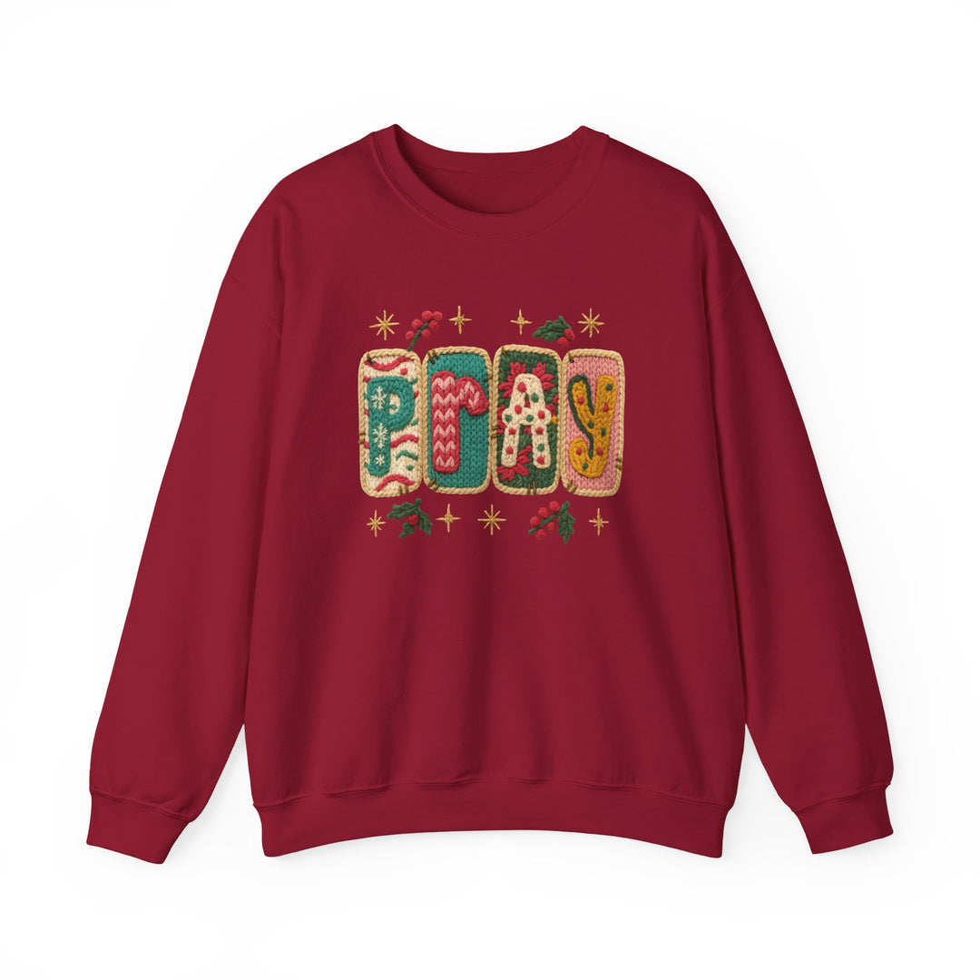 Burgundy crewneck sweatshirt featuring a festive PRAY motif with varied knit patterns, holly sprigs, and starbursts, ideal for cozy, stylish wear.