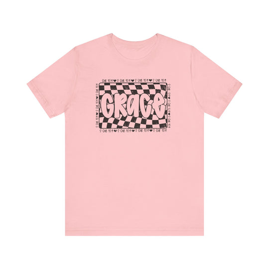 Grace Tee: A pink t-shirt featuring bold black and white text, crafted from soft cotton for a classic unisex fit with ribbed collars and durable seams.