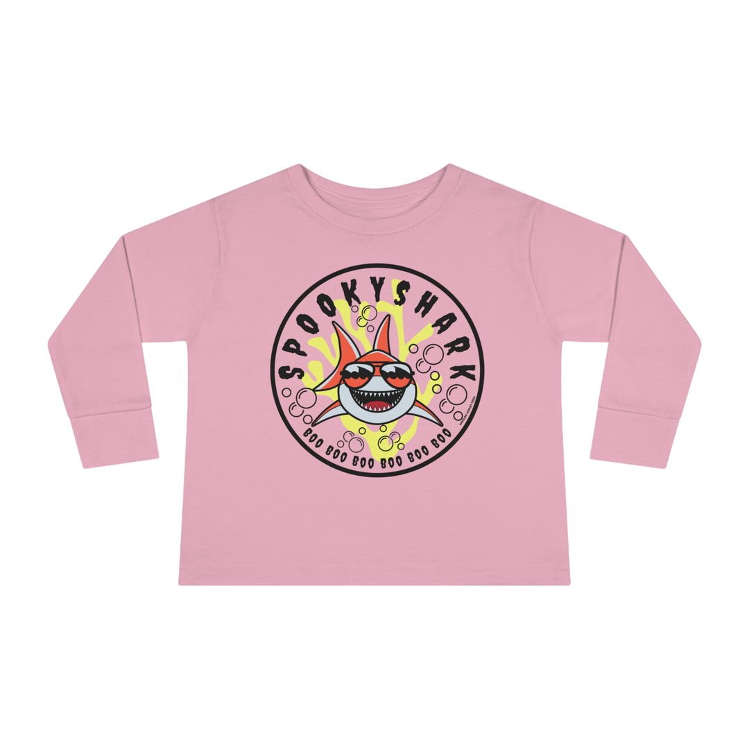 A spooky shark cartoon character adorns a pink toddler long-sleeve tee from Worlds Worst Tees. Made of 100% cotton, featuring ribbed collar and shoulder-to-shoulder taping for durability and comfort.