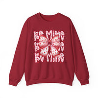 Be Mine Crew: A Valentine's Day-themed sweatshirt featuring a stylized bow and text, offering comfort with a cotton-polyester blend and ribbed knit collar.