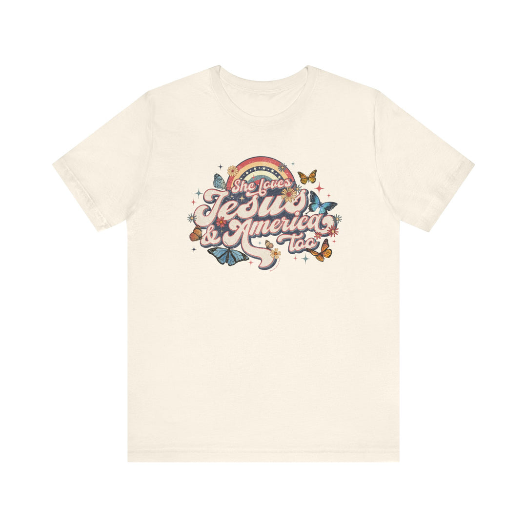A white t-shirt featuring a graphic design of butterflies and flowers, titled She Loves Jesus and America Tee. Unisex jersey tee with ribbed knit collars, taping on shoulders, and tear-away label. 100% Airlume combed cotton, retail fit.