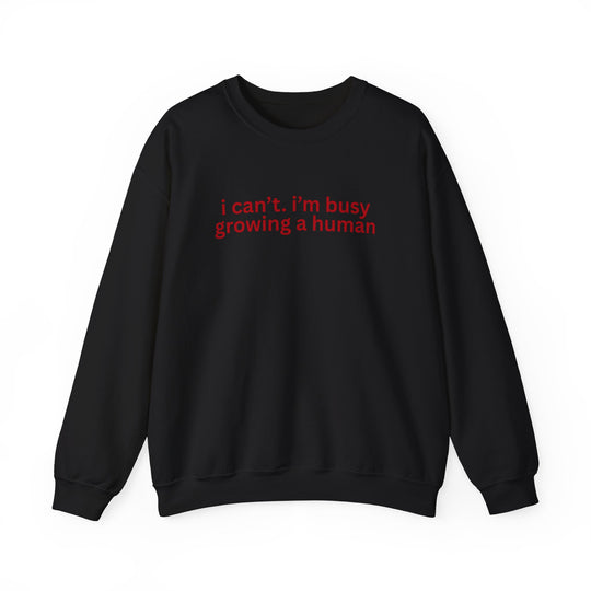 Black crewneck sweatshirt with red text: i can’t. i’m busy growing a human, ideal for maternity wear, offering comfort and playful style.