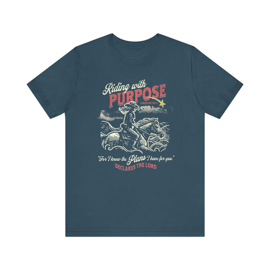 Riding for a Purpose Tee: Blue t-shirt featuring a cowboy riding a horse. Soft cotton, classic fit with ribbed collars, ideal for casual wear.