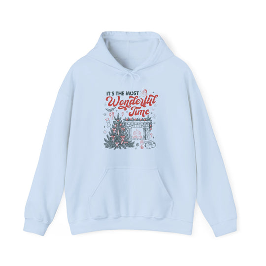 Most Wonderful Time of the Year Hoodie featuring festive Christmas graphics with fireplace, tree, and presents, offering cozy warmth with a drawstring hood and kangaroo pocket.