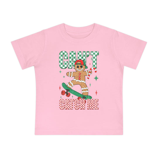 Can't Catch Me Baby Tee featuring a gingerbread character skateboarding with a candy cane, surrounded by festive text and sparkles. Perfect for stylish, comfortable toddler wear.