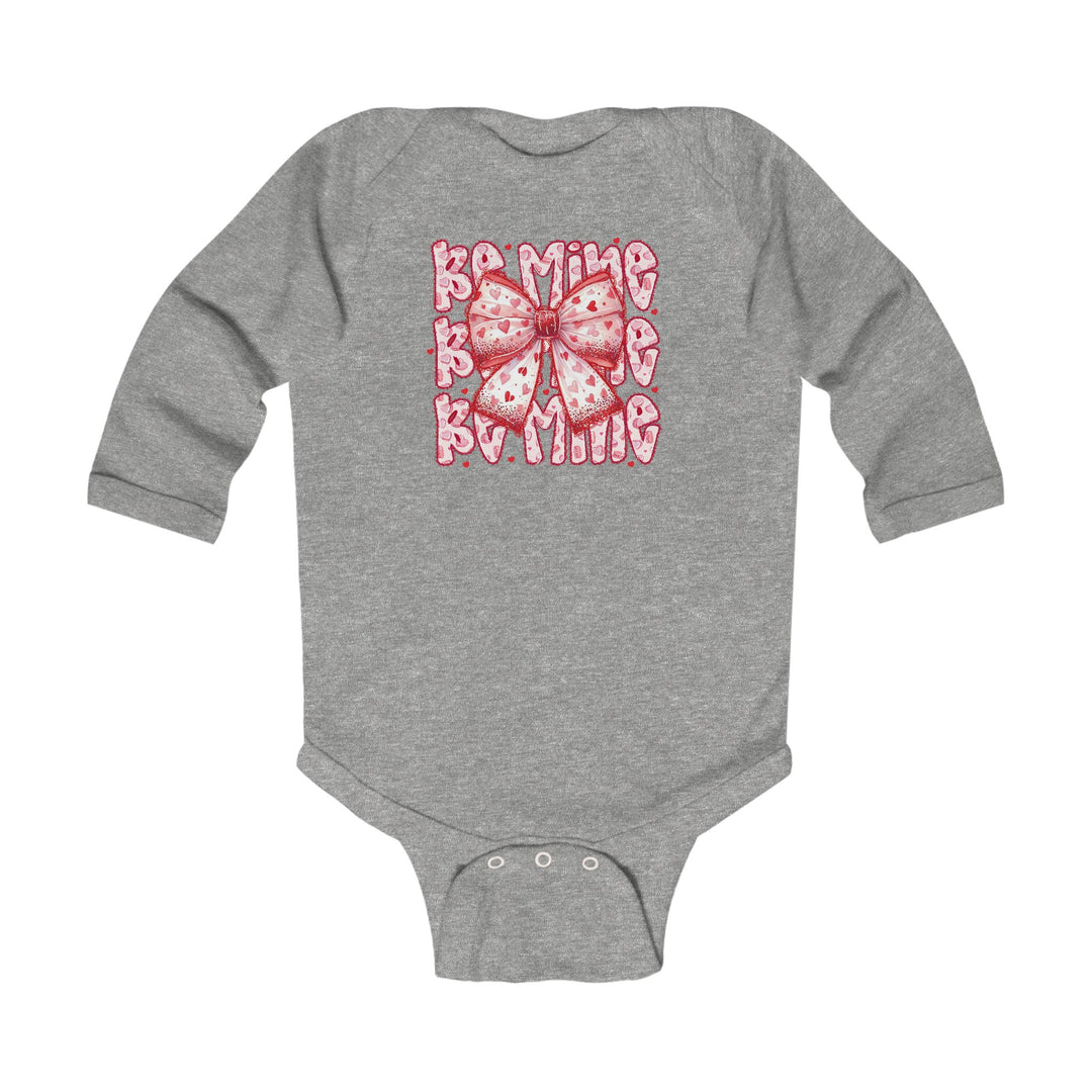 Be Mine Onesie: Heather-gray long-sleeve baby bodysuit featuring a pink-and-red heart-patterned bow, with crotch snap closures for easy changing.