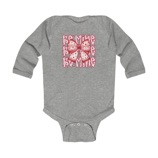Be Mine Onesie: Heather-gray long-sleeve baby bodysuit featuring a pink-and-red heart-patterned bow, with crotch snap closures for easy changing.