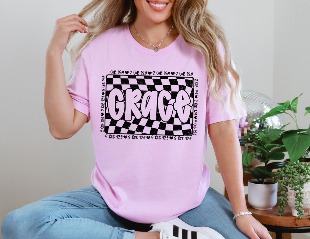 Woman sitting, wearing the Grace Tee, a unisex jersey short sleeve. Features soft cotton, ribbed knit collars, and dual side seams for lasting shape.