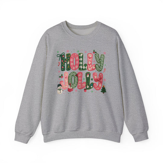 Light-gray sweatshirt with “HOLLY JOLLY” in festive letters, surrounded by Christmas motifs like snowflakes and holly, embodying cozy holiday spirit.