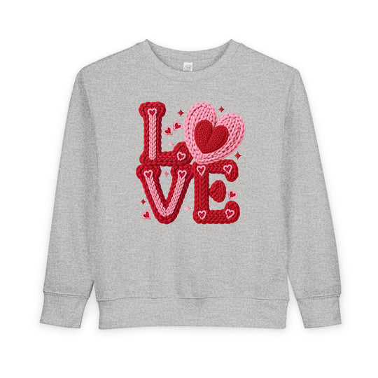 Light-gray crewneck sweatshirt with LOVE in chunky red and pink yarn letters; heart motifs included. Cozy, durable fleece for toddlers.