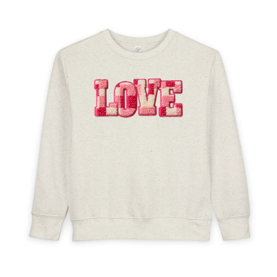 Light‐heathered off-white crewneck sweatshirt for toddlers with LOVE in plush, tufted pink and cream letters on the chest, made by Faith Family Designs.