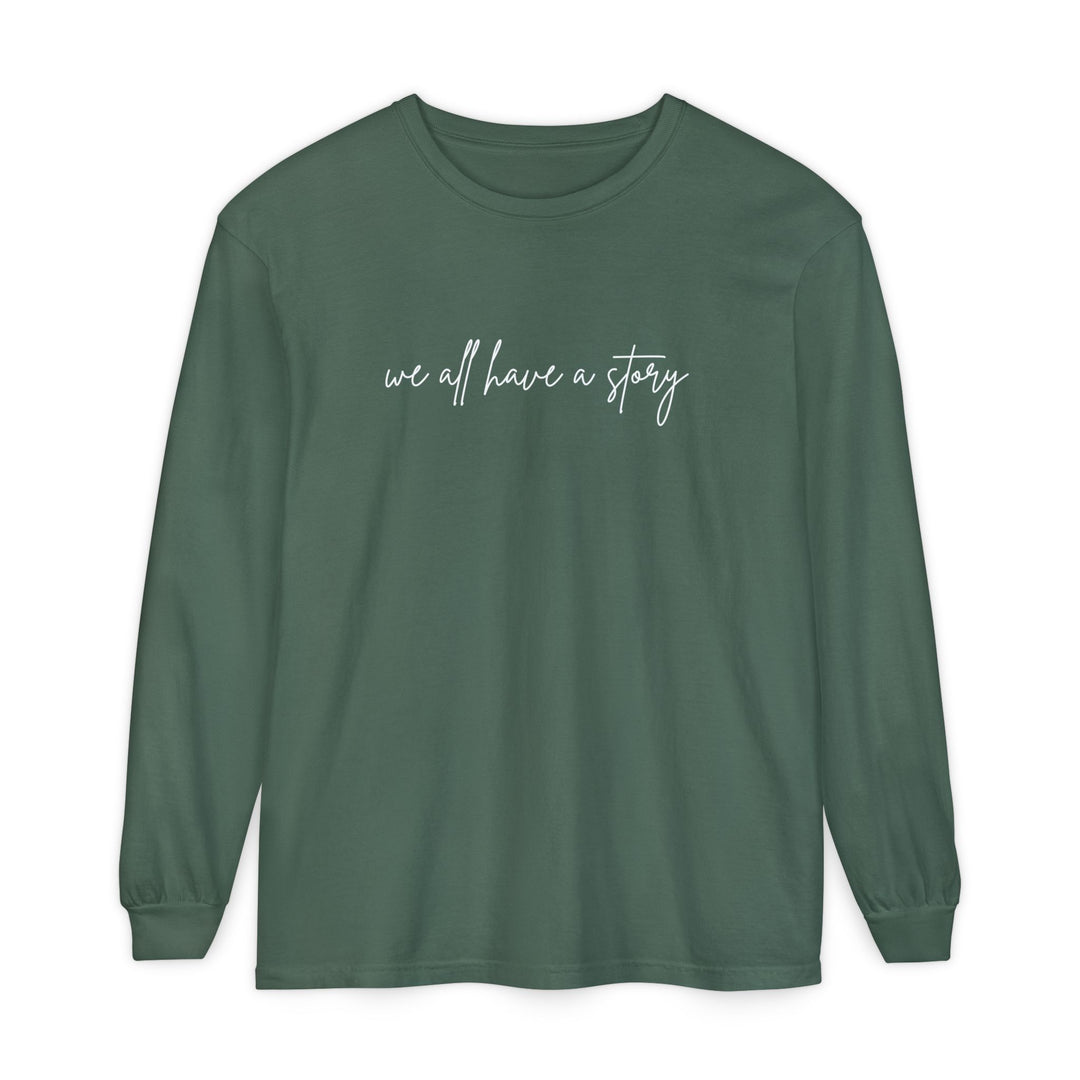 We all have a Story Long Sleeve Tee: green, long-sleeved shirt featuring white text, made from 100% ring-spun cotton with a relaxed fit.