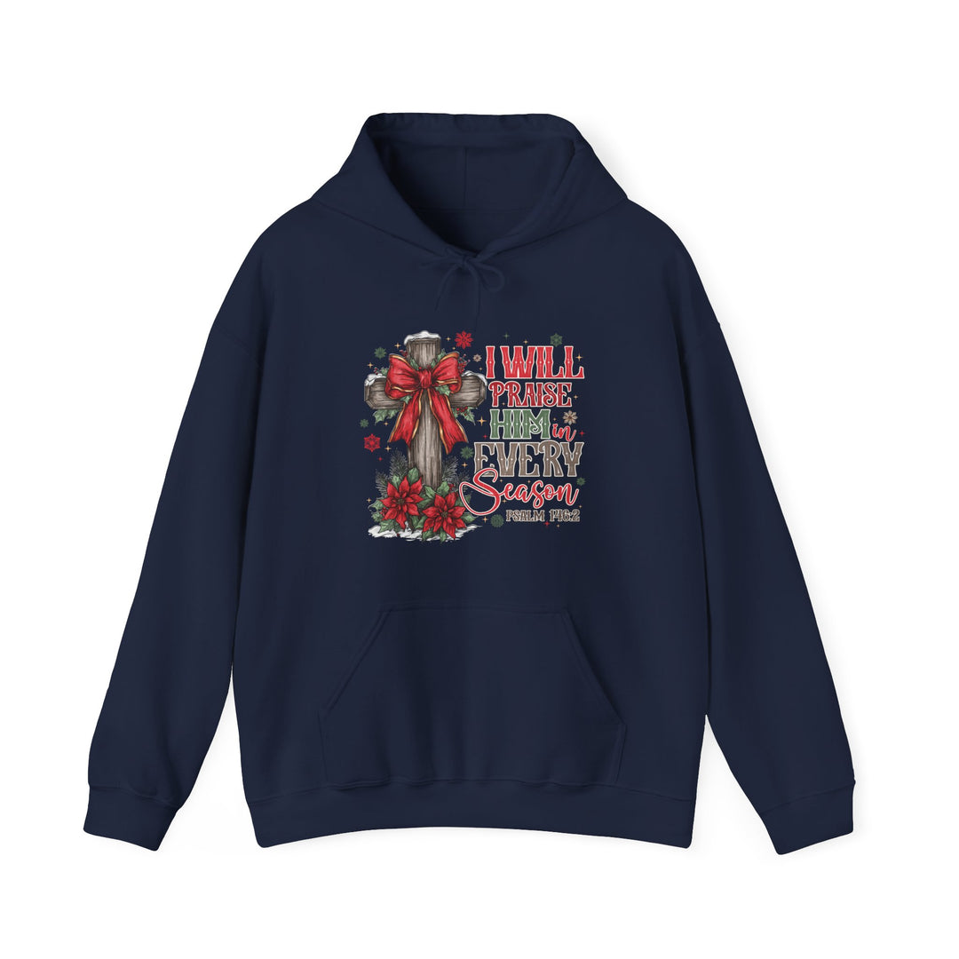 Navy-blue hoodie with a Christmas-themed Christian graphic: wooden cross with red bow, poinsettias, snowflakes, and text I WILL PRAISE HIM IN EVERY SEASON, Psalm 146:2.