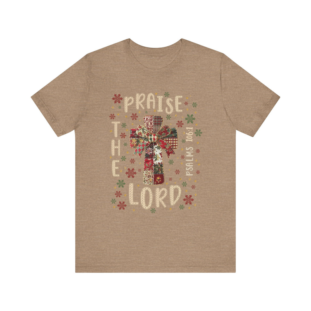 Praise the Lord Tee features a festive cross in patchwork style, surrounded by snowflake motifs, with PRAISE THE LORD and Psalms 106:1 framing it.