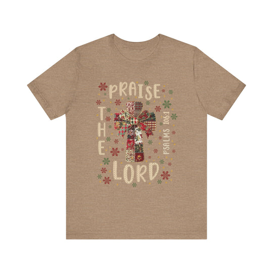Praise the Lord Tee features a festive cross in patchwork style, surrounded by snowflake motifs, with PRAISE THE LORD and Psalms 106:1 framing it.