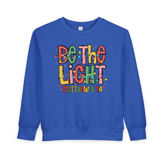 Be the Light Toddler Crew sweatshirt in bright blue features festive multi-colored graphic with Be the Light and Matthew 5:14, perfect for cozy, stylish wear.
