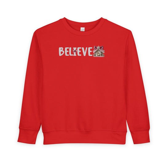 Toddler crew-neck sweatshirt with BELIEVE design featuring a Christmas ornament as I and a nativity scene as E, blending comfort with festive style.