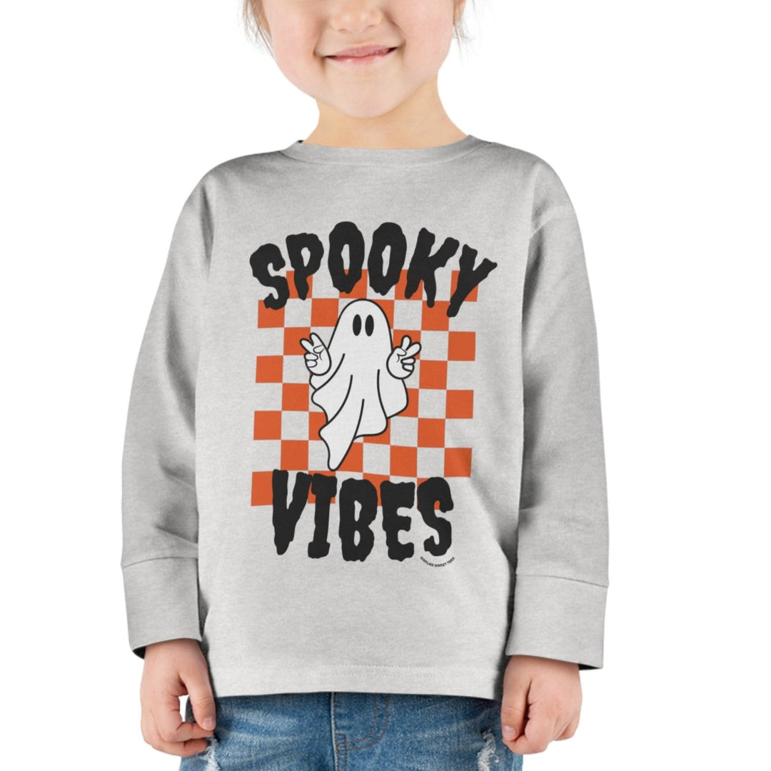 A spooky vibes toddler long sleeve tee featuring a ghost design on a white shirt. Made of 100% combed ringspun cotton, with topstitched ribbed collar and EasyTear™ label for comfort and durability.