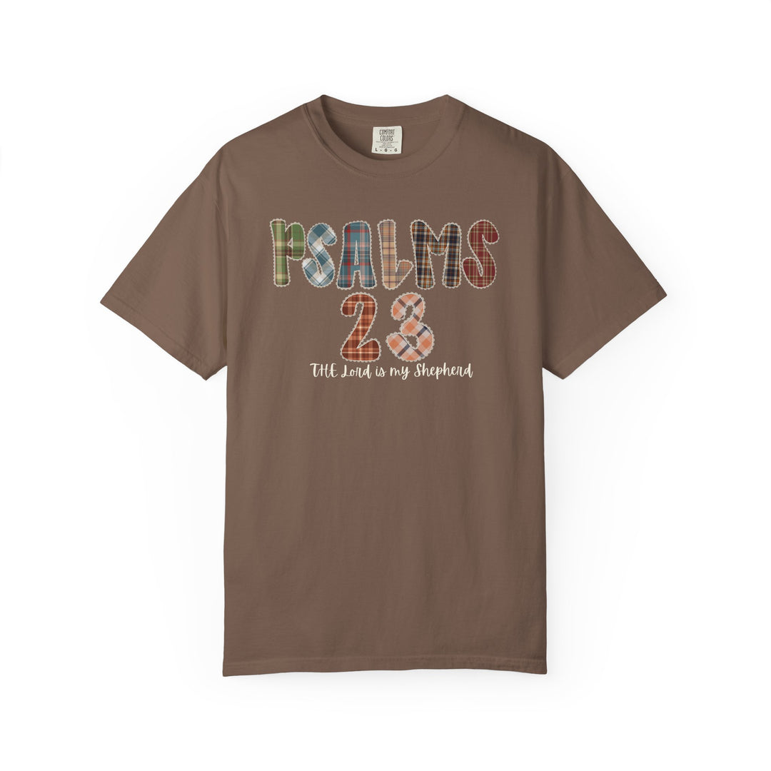 Brown short-sleeved Psalms 23 Tee with patchwork-style letters and plaid 23, featuring The Lord is my Shepherd in cursive.