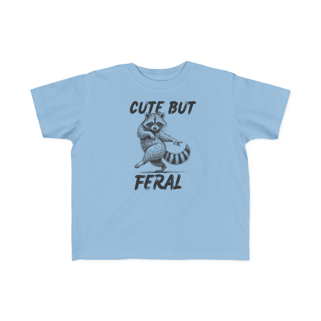 Cute but Feral Toddler Tee: Light-blue T-shirt with hand-drawn raccoon and bold “CUTE BUT FERAL” text, perfect for toddlers' sensitive skin.