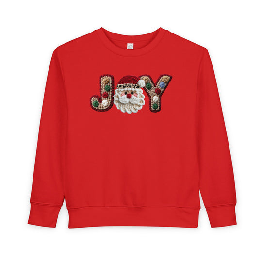 Joy Toddler Crew sweatshirt features JOY with a Santa face and pom-pom details on red fleece, offering warmth and style for toddlers.