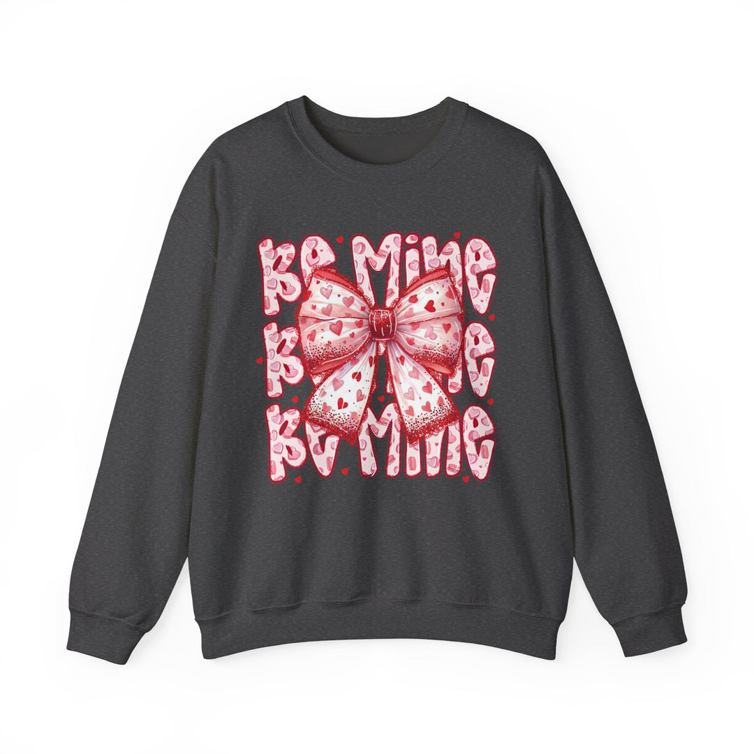 Be Mine Crew sweatshirt features a stylized pink-and-red ribbon bow with hearts, overlaying BE MINE text, capturing a playful Valentine's theme.