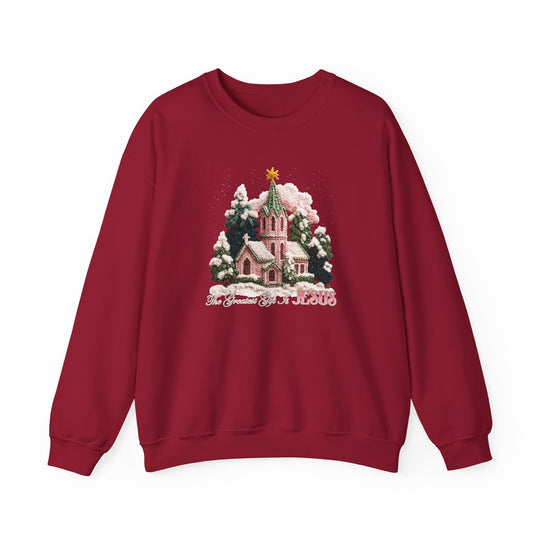 Maroon-red sweatshirt with Christmas graphic: snow-covered church, evergreen trees, glowing star, and The Greatest Gift is JESUS text, from Faith Family Designs.