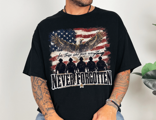 Person wearing the Never Forgotten Tee featuring a memorial graphic with an eagle, distressed flag, and soldiers, highlighting the slogan “for those who gave everything.”
