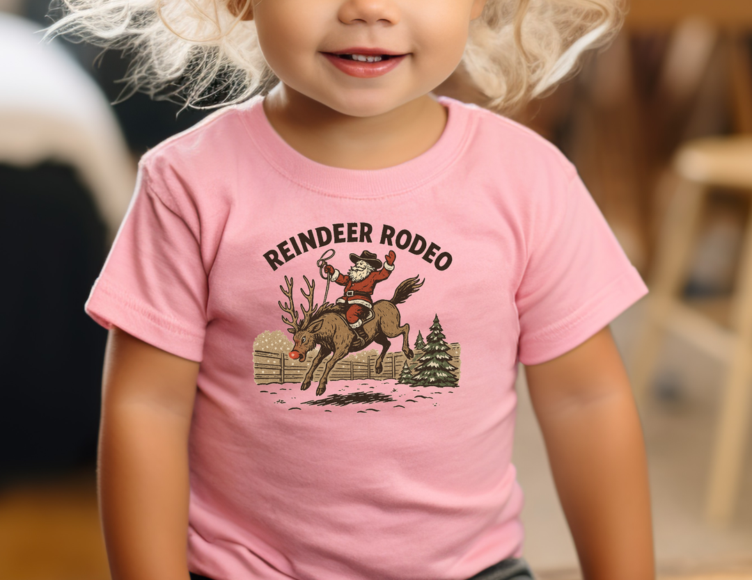 Reindeer Rodeo Baby Tee features Santa on a reindeer, perfect for stylish first steps. Super soft, durable, pre-shrunk cotton for babies.