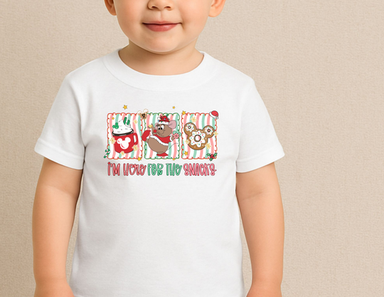 Toddler wearing Here for the Snacks baby tee featuring festive hot cocoa, Santa mouse, and gingerbread cookie graphics.