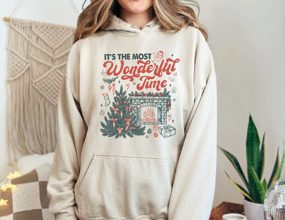 Person wearing the Most Wonderful Time of the Year Hoodie, featuring a festive Christmas scene with text and illustrations, highlighting warmth and comfort for cold days.